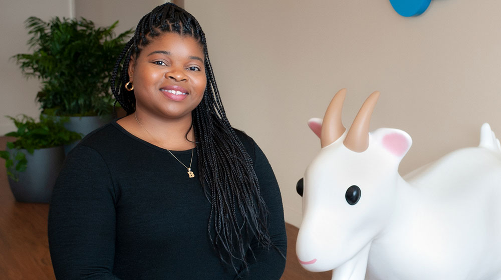 Brittney Marshall standing in front of SalesForce mascot, Cloudy the Goat.